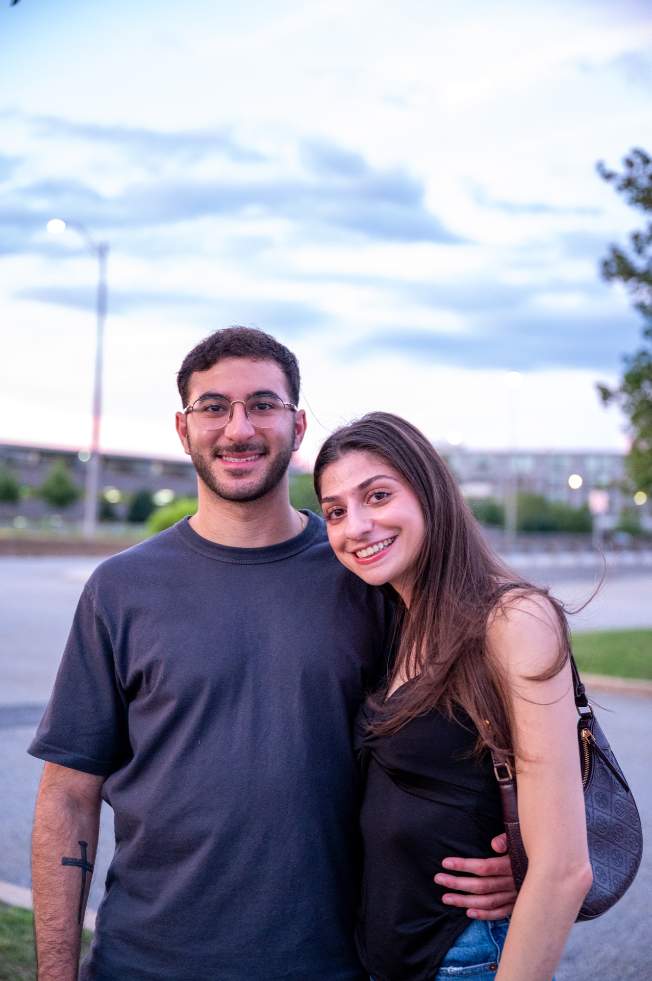 A smiling couple beneath a soft evening sky