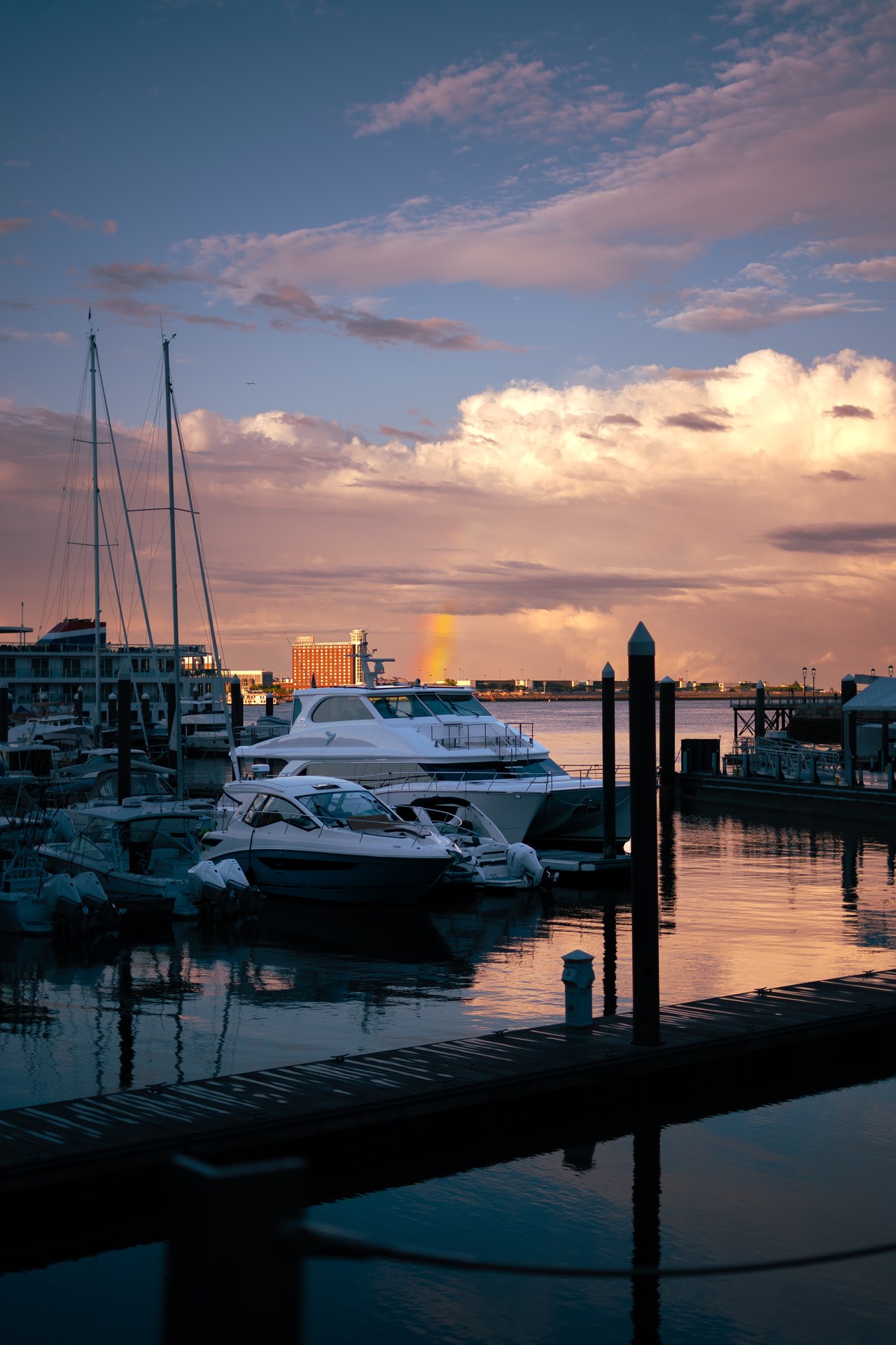 Sailboats and masts silhouetted beneath a colorful sunset sky