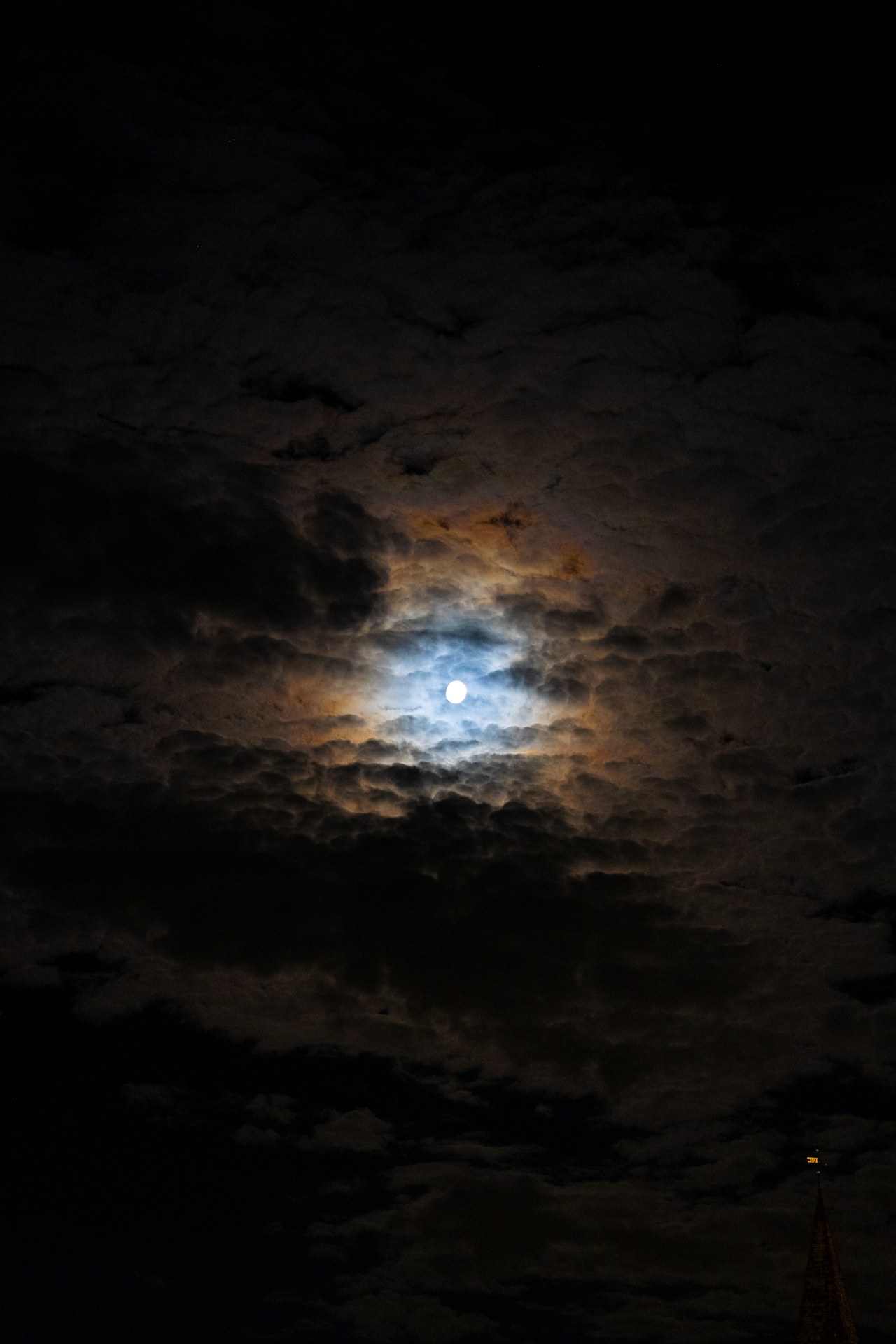 Moonlight breaking through clouds in a dark night sky