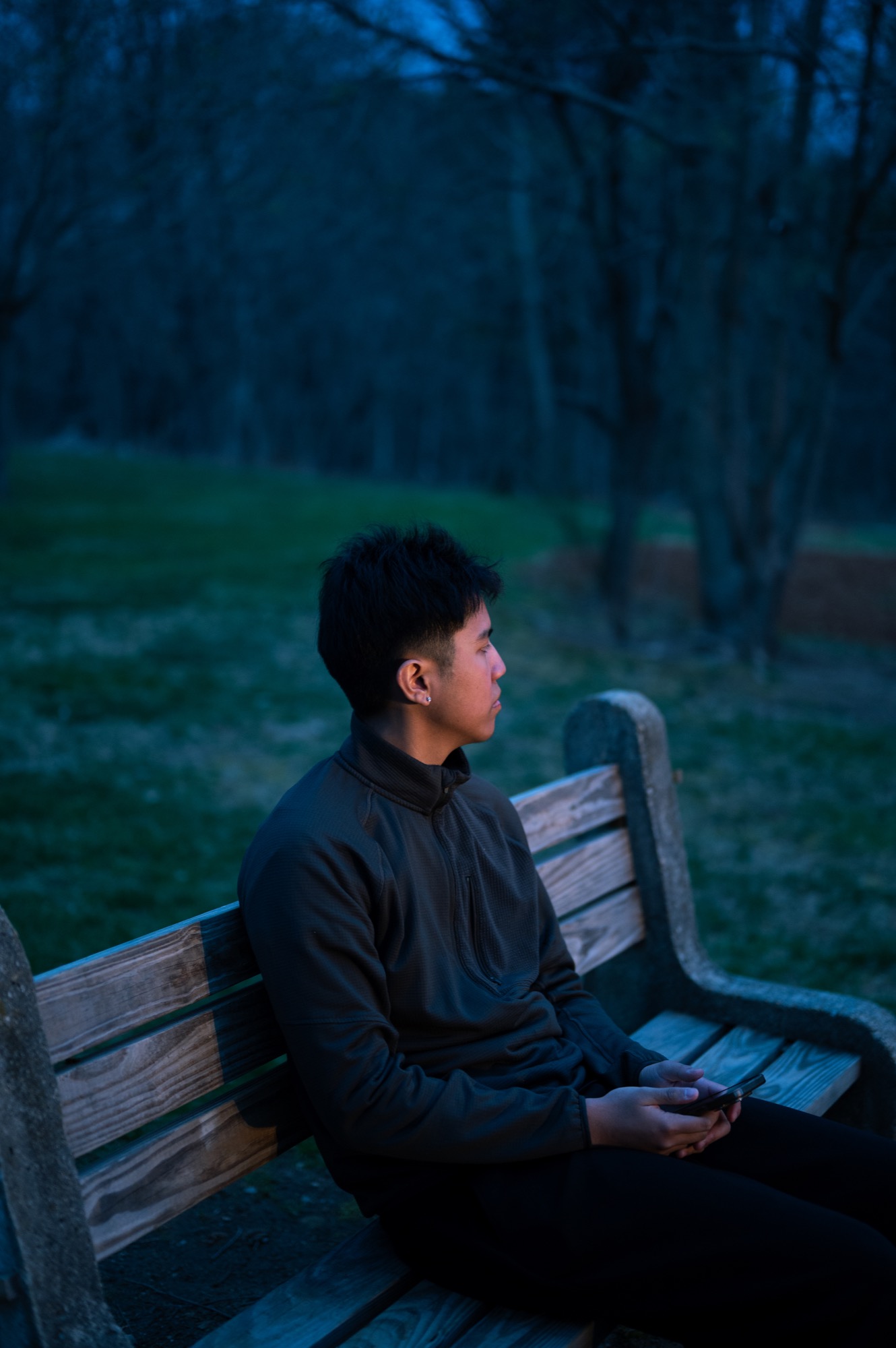 A quiet portrait on a park bench in deep blue evening light